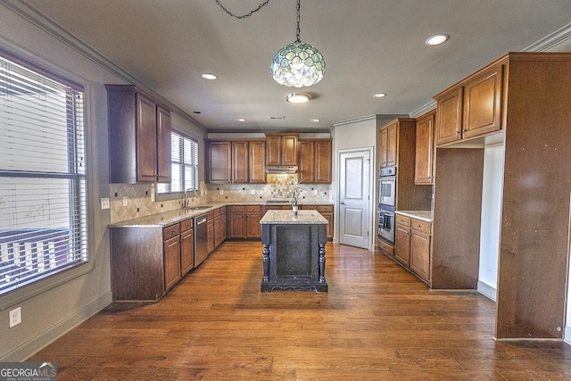 kitchen featuring crown molding, dark wood-style flooring, a sink, and under cabinet range hood