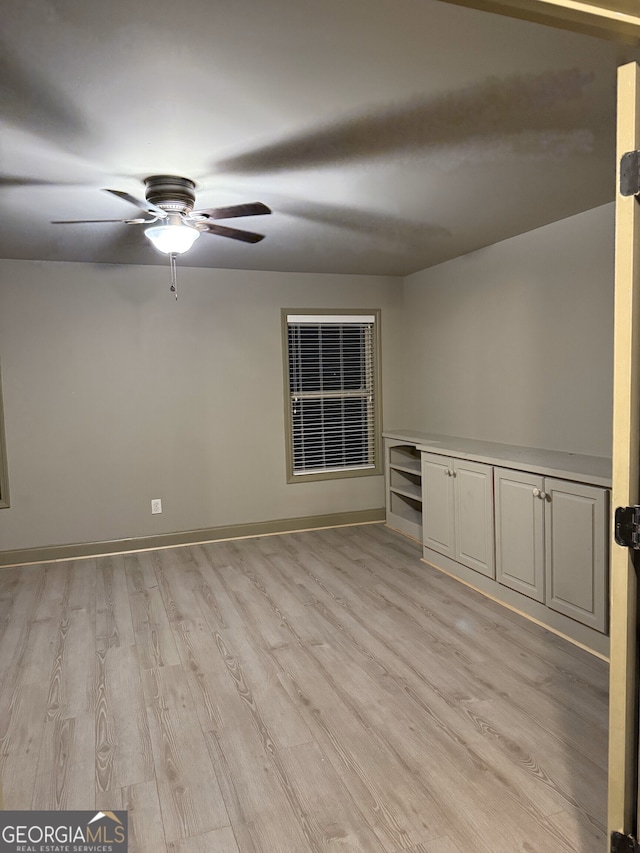 unfurnished room with ceiling fan, light wood-style flooring, and baseboards