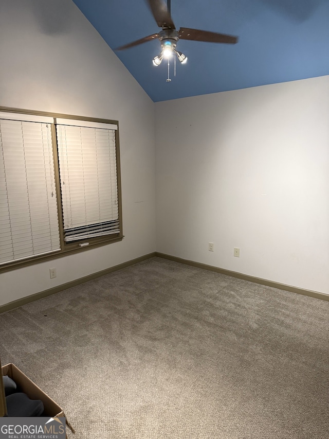 carpeted spare room featuring ceiling fan, baseboards, and vaulted ceiling