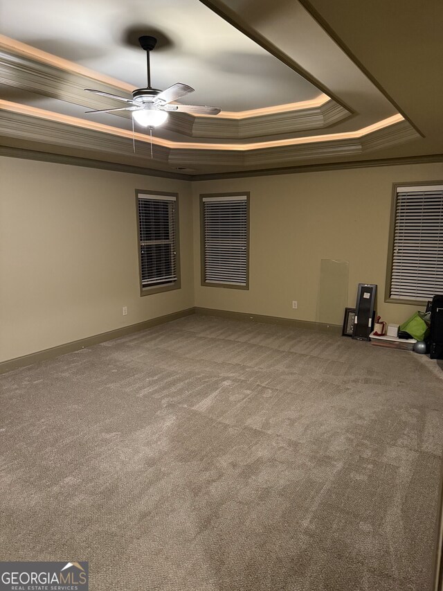 unfurnished living room featuring baseboards, a tray ceiling, carpet flooring, and ornamental molding