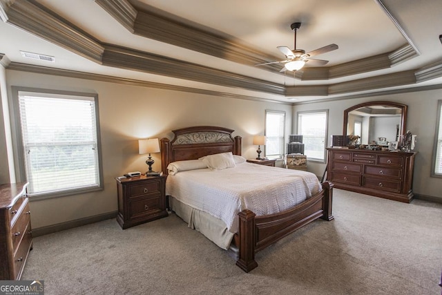 bedroom featuring a raised ceiling, crown molding, ceiling fan, and light carpet