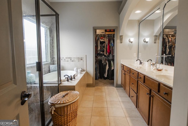 bathroom featuring tile patterned flooring, vanity, and tiled tub