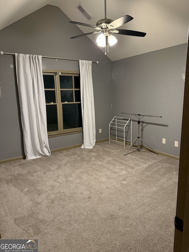 carpeted spare room featuring visible vents, vaulted ceiling, baseboards, and ceiling fan