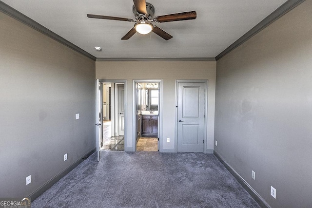 unfurnished bedroom featuring carpet floors, ensuite bathroom, ornamental molding, a ceiling fan, and baseboards