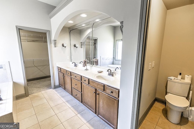 bathroom featuring double vanity, toilet, tile patterned flooring, a spacious closet, and a sink