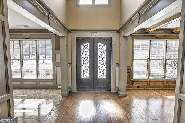 foyer entrance featuring wood-type flooring, a high ceiling, and french doors