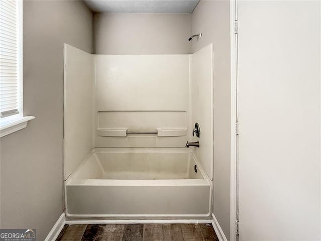 bathroom with hardwood / wood-style flooring and bathing tub / shower combination