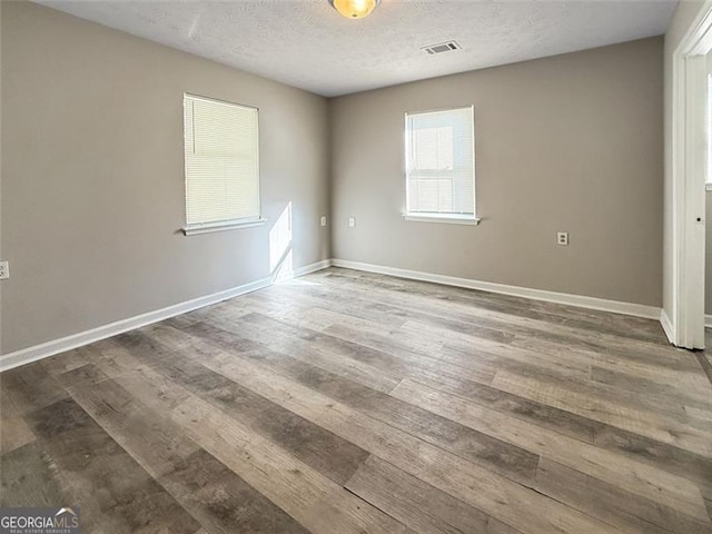 unfurnished room with dark hardwood / wood-style flooring and a textured ceiling