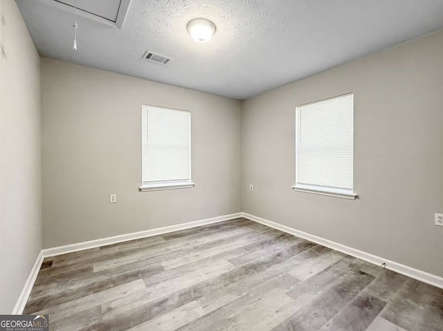 spare room featuring hardwood / wood-style floors and a textured ceiling