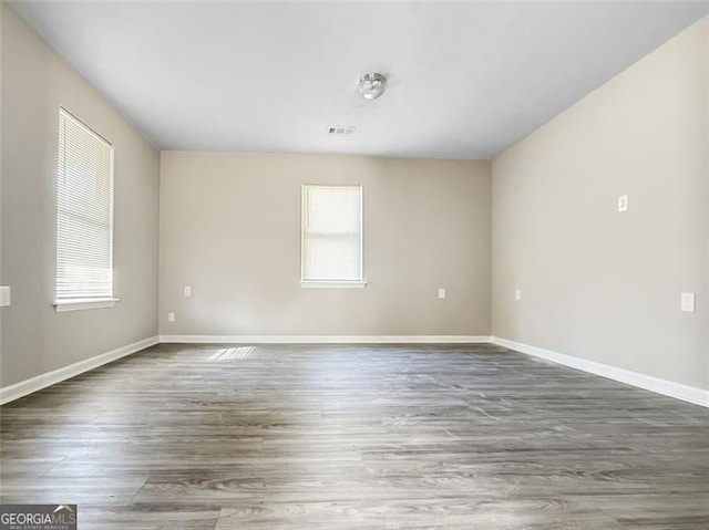 unfurnished room featuring a healthy amount of sunlight and dark hardwood / wood-style flooring