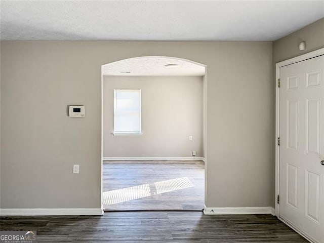 spare room featuring dark hardwood / wood-style floors and a textured ceiling