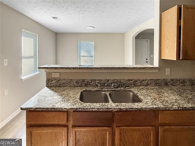 kitchen with light stone countertops, sink, and a textured ceiling