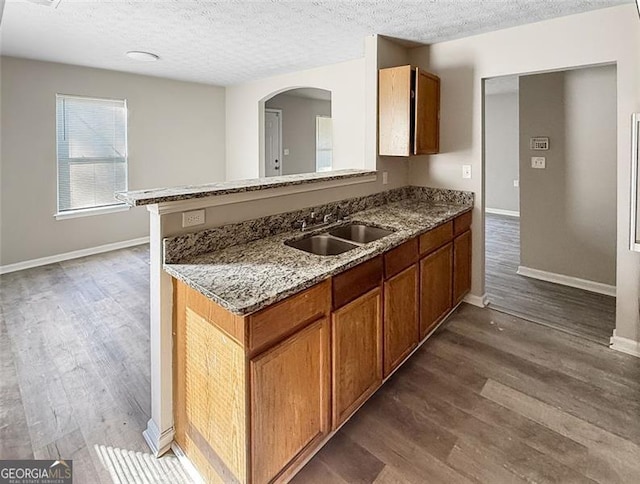 kitchen with dark hardwood / wood-style floors, light stone countertops, sink, and a textured ceiling