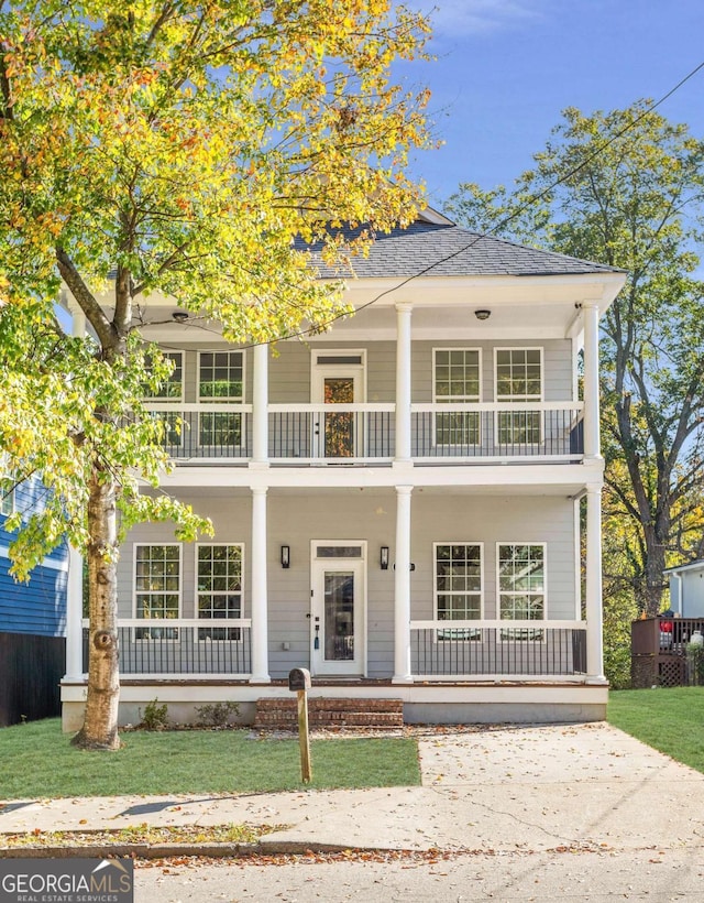 view of front of house featuring a front lawn, covered porch, and a balcony