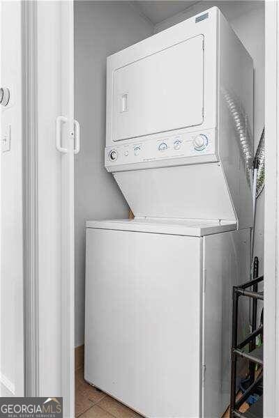 laundry room featuring stacked washer and dryer and light tile patterned floors