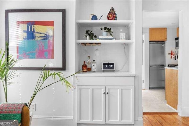 bar with appliances with stainless steel finishes, white cabinetry, and light wood-type flooring