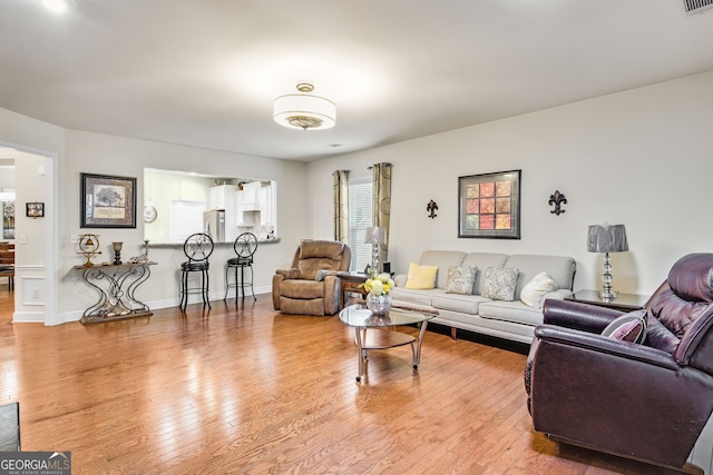 living area with wood-type flooring, visible vents, and baseboards