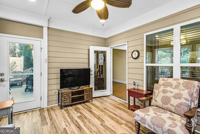 interior space featuring ornamental molding, ceiling fan, wooden walls, and wood finished floors