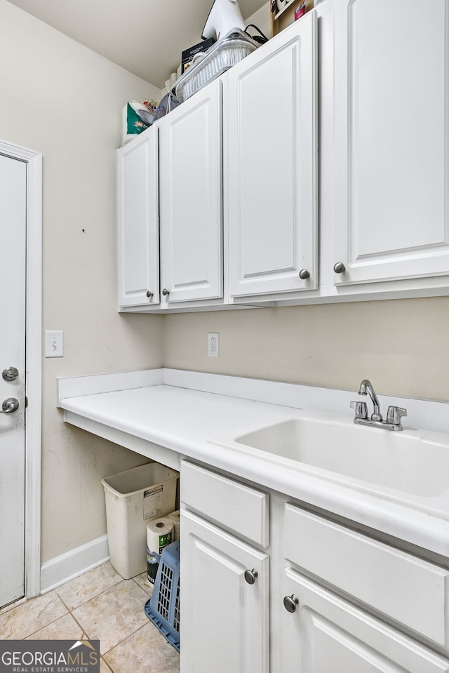 laundry room with a sink, baseboards, and light tile patterned floors