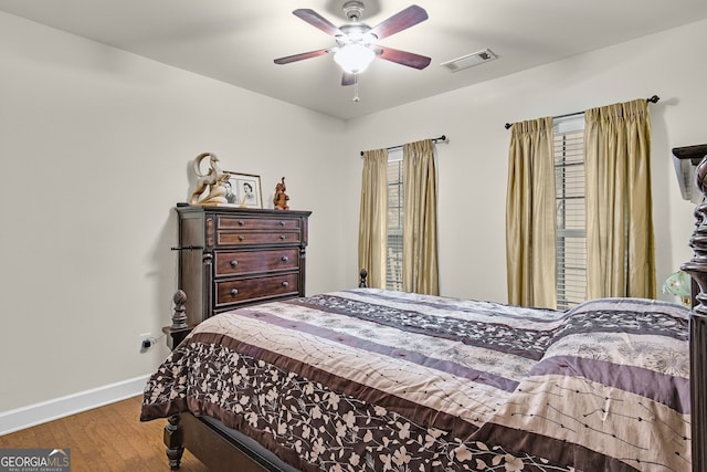 bedroom featuring visible vents, ceiling fan, baseboards, and wood finished floors