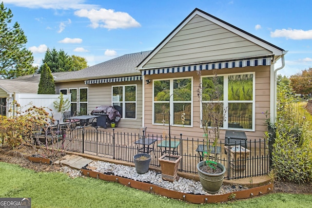 back of house with a shingled roof, fence, and a patio