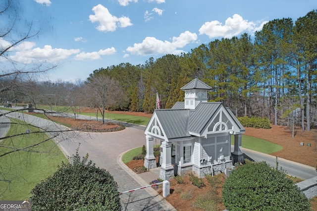 view of community featuring driveway, a yard, and a view of trees