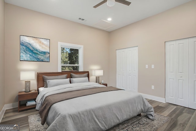 bedroom featuring dark hardwood / wood-style flooring, ceiling fan, and multiple closets