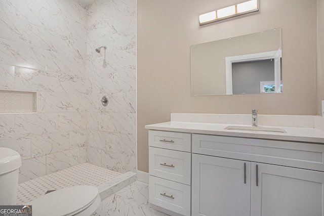 bathroom with toilet, vanity, and a tile shower