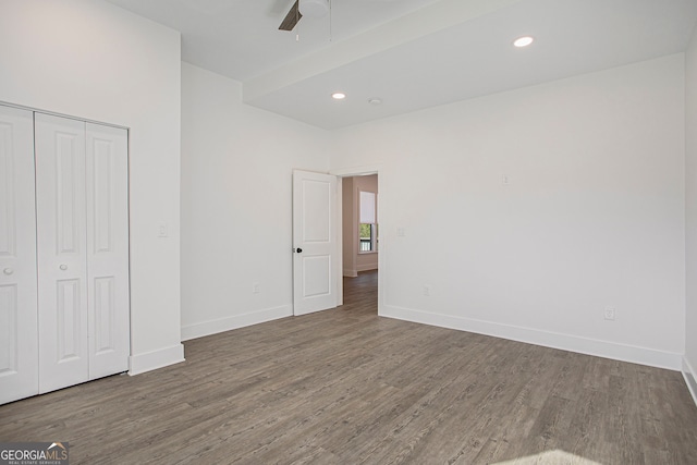 unfurnished bedroom with dark hardwood / wood-style flooring, a closet, and ceiling fan