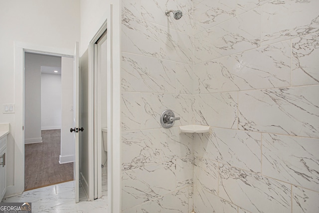 bathroom featuring hardwood / wood-style floors, vanity, and a tile shower