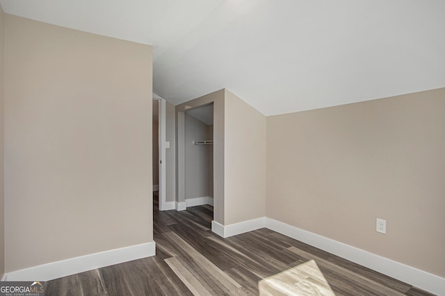 interior space featuring a walk in closet, dark hardwood / wood-style floors, a closet, and vaulted ceiling