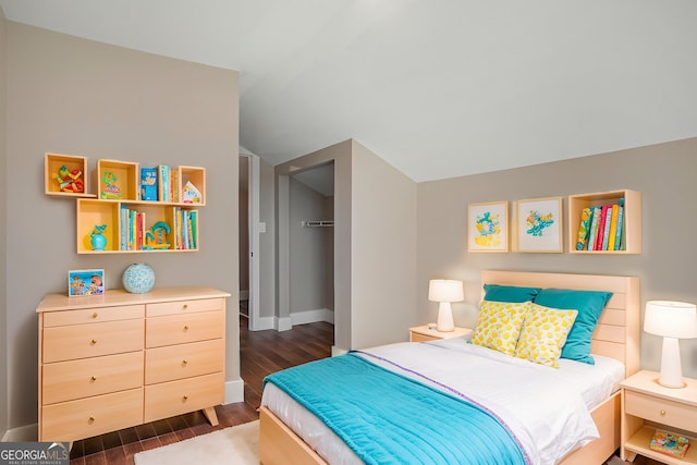 bedroom featuring dark hardwood / wood-style floors, vaulted ceiling, a walk in closet, and a closet