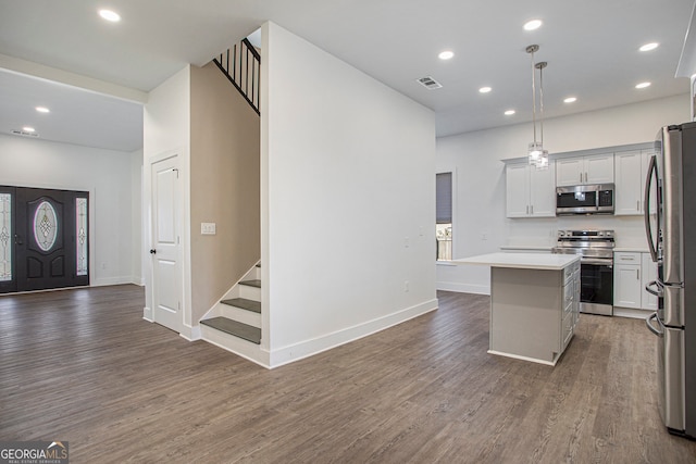 kitchen featuring stainless steel appliances, decorative light fixtures, dark hardwood / wood-style floors, and a kitchen island