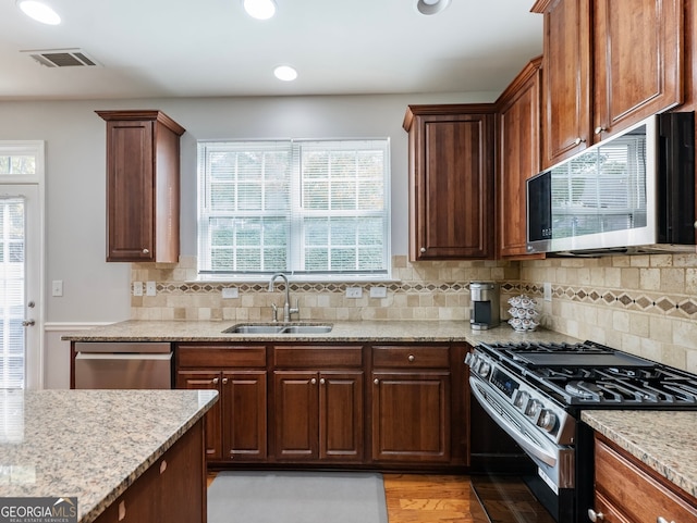 kitchen featuring light hardwood / wood-style floors, stainless steel appliances, tasteful backsplash, and sink