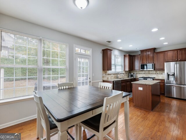 kitchen with tasteful backsplash, appliances with stainless steel finishes, sink, light hardwood / wood-style floors, and a center island