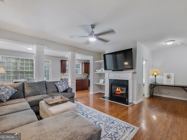 living room featuring hardwood / wood-style floors, ornate columns, and ceiling fan