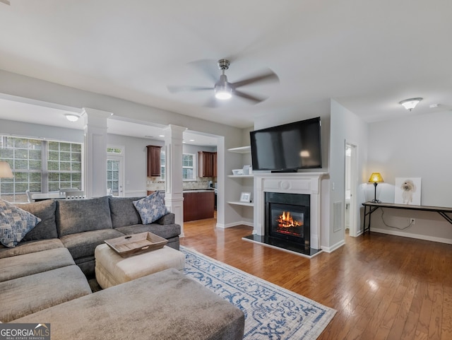 2397 Sardis Chase Ct, Buford, GA 30519 - living room featuring ornate columns, ceiling fan, wood finished floors, a glass covered fireplace, and baseboards