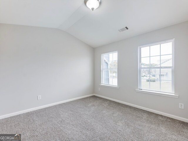 carpeted spare room with lofted ceiling