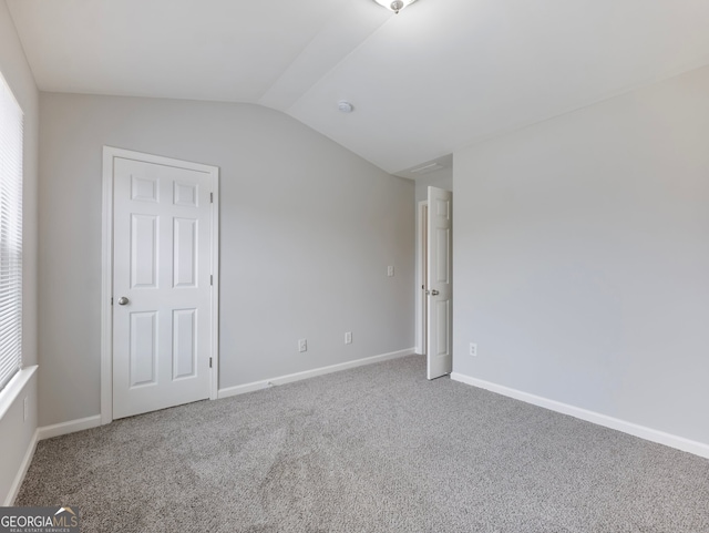 carpeted empty room featuring lofted ceiling