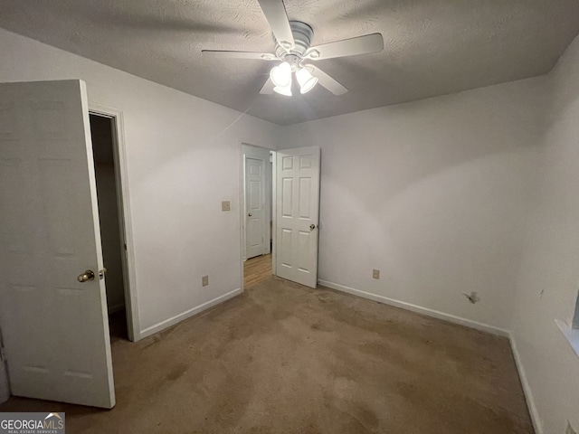 unfurnished bedroom with light colored carpet, a textured ceiling, and baseboards