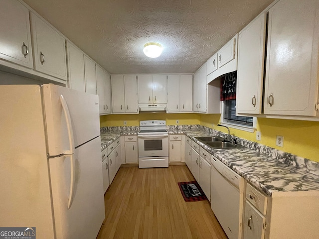 kitchen featuring white appliances, white cabinets, light wood-style flooring, under cabinet range hood, and a sink