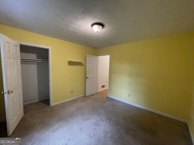 unfurnished bedroom featuring a textured ceiling, baseboards, a closet, and carpet flooring