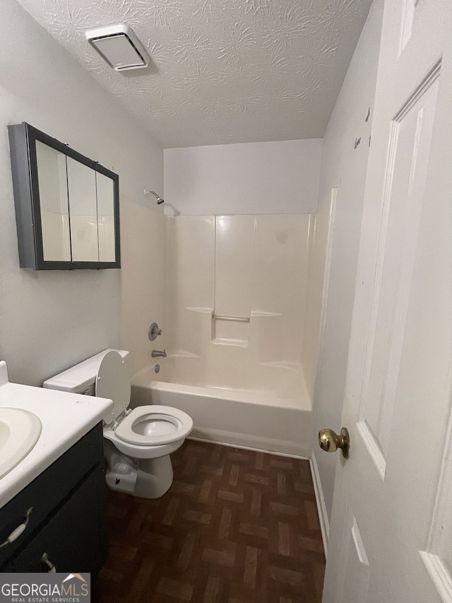 full bathroom featuring a textured ceiling,  shower combination, vanity, and toilet