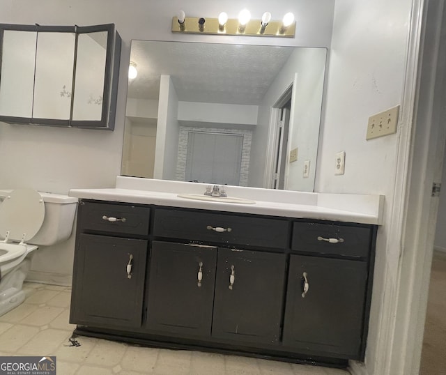 bathroom featuring a textured ceiling, vanity, and toilet