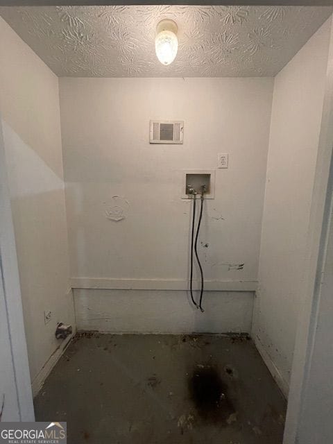 clothes washing area with laundry area, hookup for a washing machine, a textured ceiling, visible vents, and baseboards