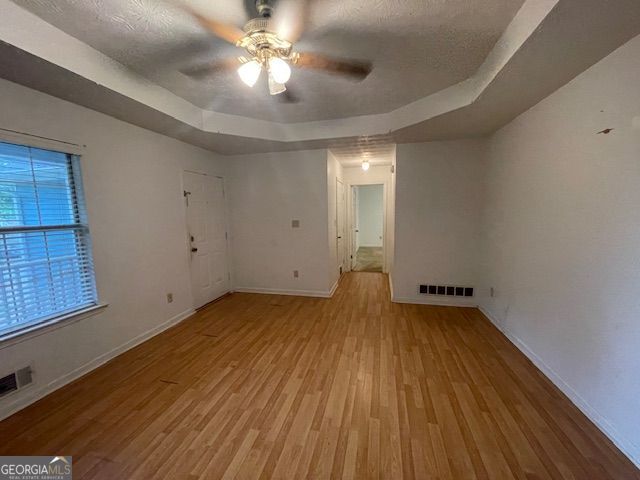 unfurnished room featuring baseboards, a raised ceiling, visible vents, and light wood-style floors