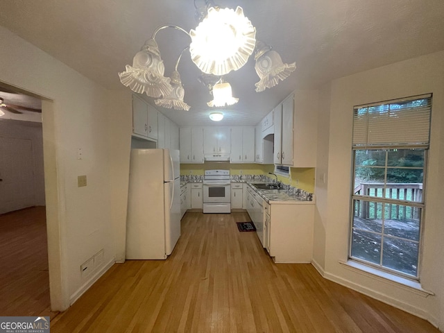 kitchen with a sink, white appliances, light wood-style flooring, white cabinets, and a notable chandelier
