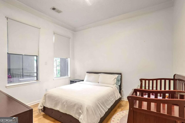 bedroom featuring light hardwood / wood-style flooring and crown molding