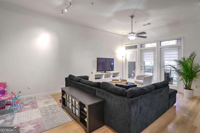 living room featuring track lighting, a textured ceiling, ceiling fan, crown molding, and light hardwood / wood-style flooring