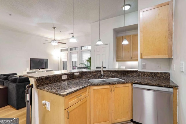 kitchen featuring stainless steel dishwasher, sink, a textured ceiling, and dark stone counters